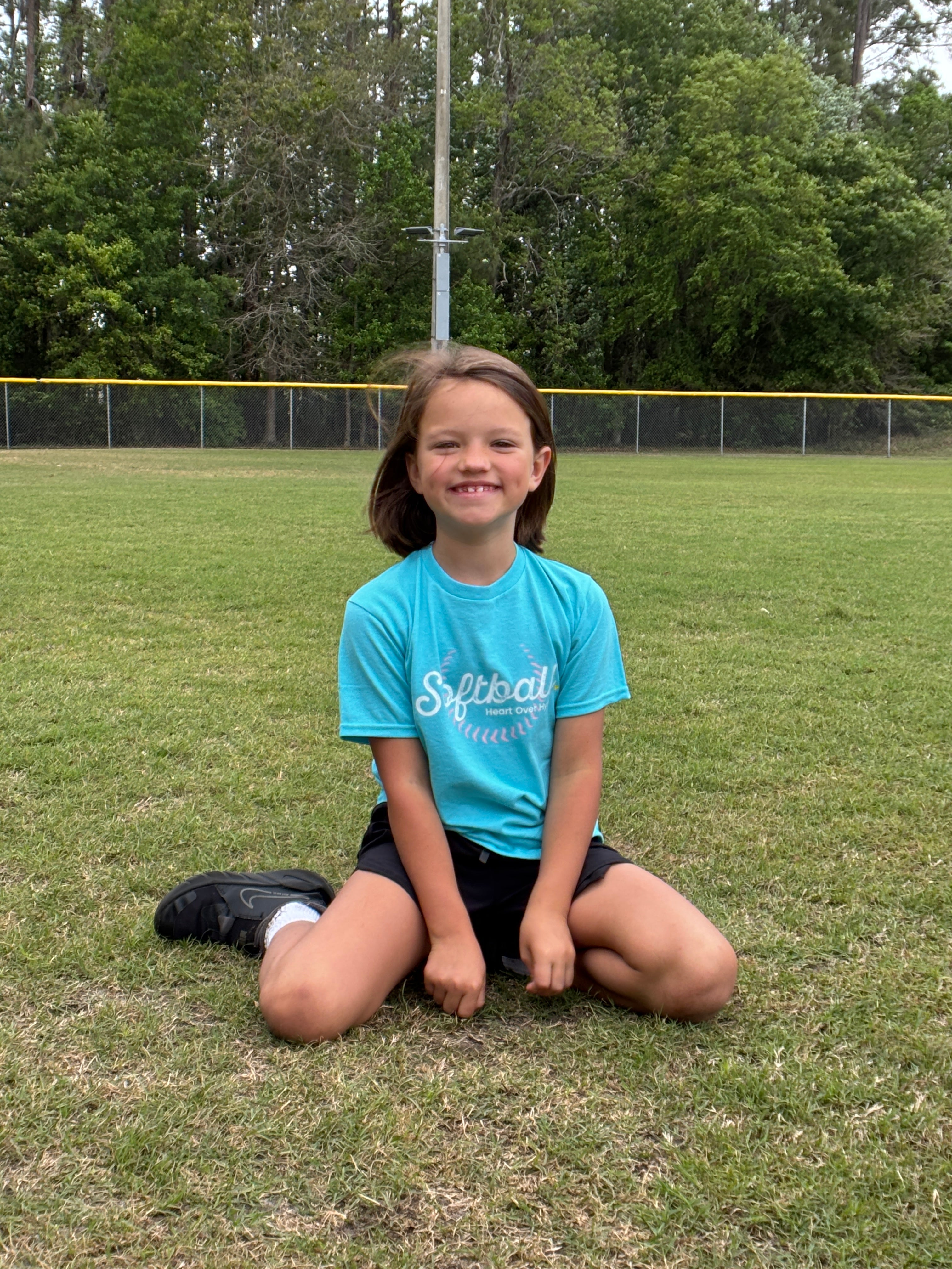 girl age 8 smiling with a prep step softball tshirt on